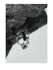 Detailed shot of rectangular black gemstone ring with small zircon on mirror and charcoal