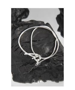 Detailed view of silver S925 snake chain bracelet with spring ring clasp on black wood