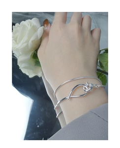 Detail of minimalist double-layer S925 silver snake chain bracelet worn with floral decor