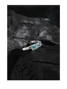 Macro view of S925 sterling silver ring with blue gemstone on black rock background