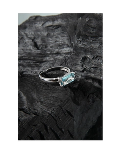 Macro shot of liquid metal silver ring featuring a blue rectangular zircon on charcoal