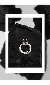 Detail of silver heart padlock charm and white pearl chain ring on charcoal background