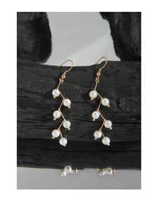 Detail of elegant S925 silver pearl drop earrings with gold wire on black wood