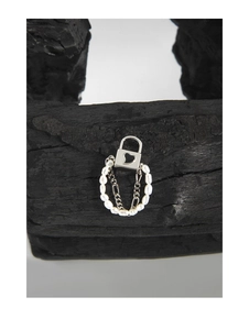 Macro shot of silver heart lock ring with pearls and chains on a dark charcoal texture