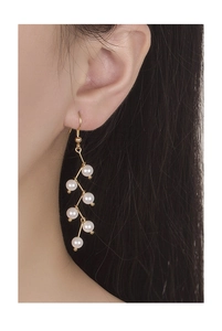 Elegant gold drop earrings with tiered pearl fringe worn by a model in a side view