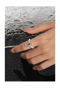 Detail of beaded pearl ring featuring a silver heart padlock charm on a model's finger