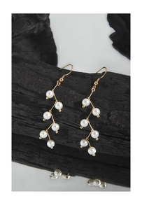 Detail of elegant gold S925 silver hook earrings with white pearl strands on dark background