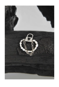 Macro detail of S925 silver padlock charm with heart motif and white pearls on chain