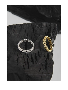 Detailed close-up of gold and silver chain rings with pavé crystals on black charcoal