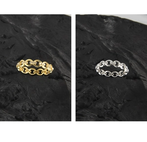 Macro detail of gold and silver chain link rings with micro-pave stones on black stone
