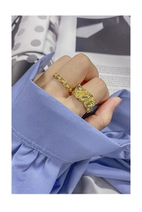 Detail of minimalist gold chain ring and wide irregular textured ring on hand