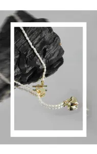 Detailed close-up of a pearl necklace with golden heart pendant and toggle clasp