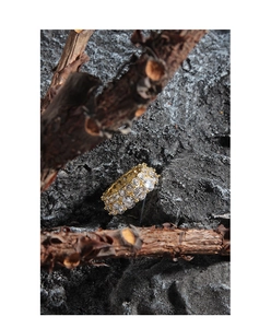Close-up of double-row gold-plated cubic zirconia ring on natural stone background