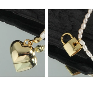 Detailed macro view of S925 silver heart and lock charms on a pearl necklace