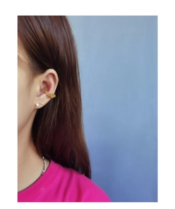 Detail of gold ear cuff and arrow stud earring worn by model in a stylish jewelry set