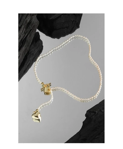 Macro detail of S925 silver pearl necklace with gold heart pendant and OT clasp