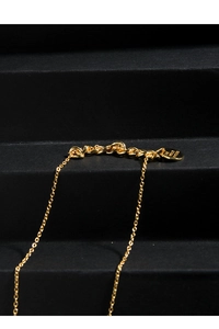 Detailed macro view of gold-plated pendant engraved with The World Is Yours text