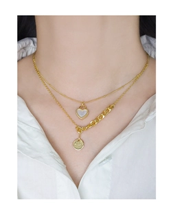 Detail of layered gold S925 necklace with heart pendant and engraved round charm