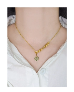 Detail of gold coin necklace engraved with THE WORLD IS YOURS on a white shirt