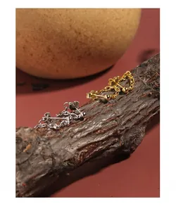 Macro shot of S925 sterling silver chain stud earrings on rustic bark texture