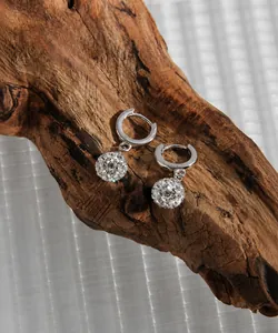 Detail of silver S925 disco ball charm hoop earrings displayed on a wood texture