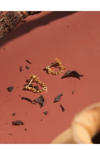 Detailed shot of gold geometric chain earrings on an aesthetic textured background
