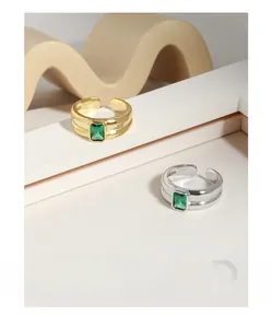 Macro view of wide silver ring with emerald cut green zircon and linear details
