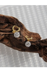 Macro shot of gold hoop earrings with pave disco ball pendants on dark wood