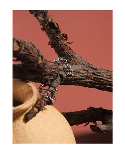 Artistic detail of S925 sterling silver chain earrings on a natural ceramic background