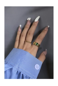Detail of stacked gold rings featuring rectangular emerald green zircon on model finger