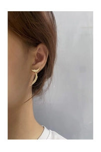 Macro view of gold curved feather earrings featuring micro-pave cubic zirconia crystals