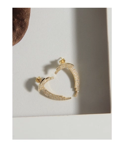 Macro detail of gold plated heart shaped earrings with micro-set zircon stones