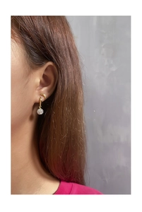 Detailed view of gold disco ball earrings with cubic zirconia on a model's ear