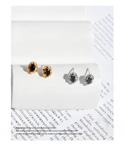 Vue détaillée de clous d'oreilles ovales en zircon noir aux finitions or et argent