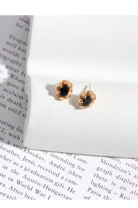 Gros plan de boucles d'oreilles ovales dorées avec zircon noir et texture rétro