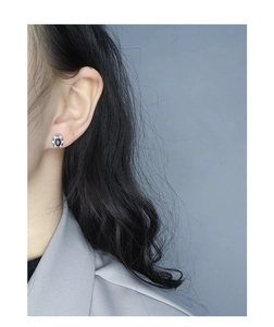 Gros plan d'une boucle d'oreille en argent S925 avec pierre noire sur l'oreille