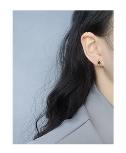 Détail de puce d'oreille en argent s925 avec zircon noir et bordure dorée ondulée sur modèle