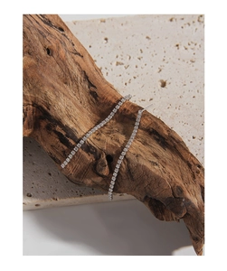 Detail of S925 silver tennis chain earrings with micro-set zircons on rustic wood stand
