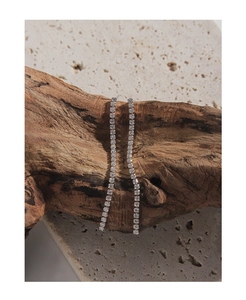 Detail of silver long tassel earrings with pavé zircons hanging on a natural wood branch