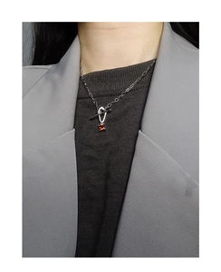 Silver OT clasp necklace with rectangular red gemstone pendant worn over a blazer