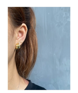 Close-up of elegant gold geometric layered shell earrings worn on a female ear