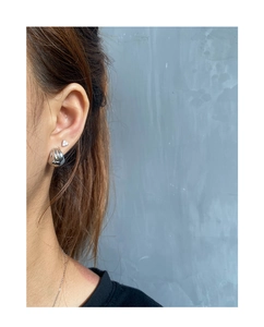 Close-up of a silver ribbed dome ear cuff and triangle stud earring on a model