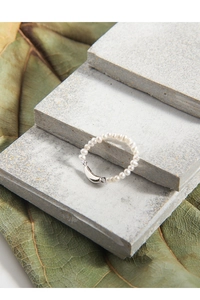Detailed macro view of a 925 silver freshwater pearl ring on grey geometric stone blocks