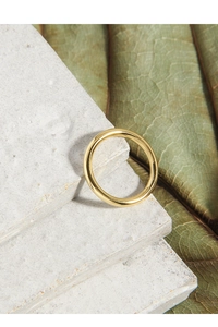 Dettaglio dell'anello dorato lucido su pietra naturale e foglia per uno stile sobrio