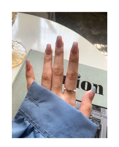 Detail of beaded pearl ring and gradient blue square false nails on a model hand