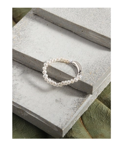 Detail of freshwater pearl ring with silver curved bar on textured stone surface