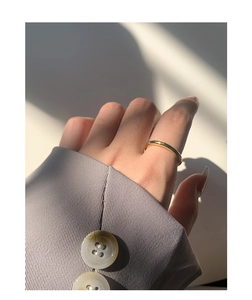 Primo piano di un anello minimalista in oro lucido indossato al dito con luce naturale