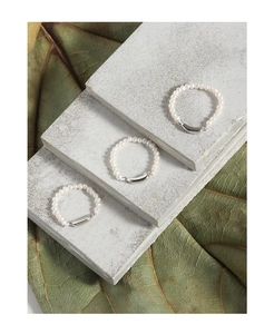 Detailed view of beaded pearl rings with curved silver accents on stone display