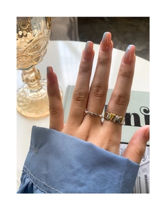 Close-up of minimalist pearl ring and gold-silver heart chain ring on hand