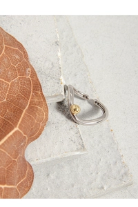 Macro detail of minimalist dual-tone silver and gold ear cuff on natural stone texture